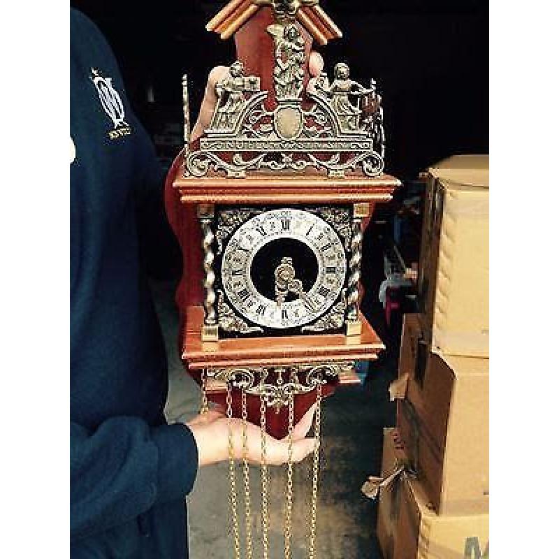 Wall mounted ornate clock in dark wood and brass finish.